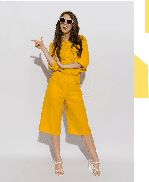 A woman in yellow outfit posing with finger guns and sunglasses.