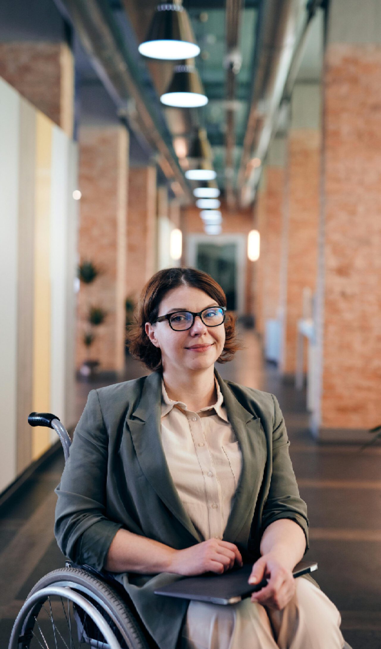 A confident woman in a wheelchair smiling in a modern office.