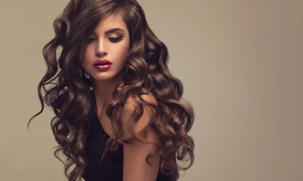 Woman with long, voluminous curly hair and a contemplative expression.