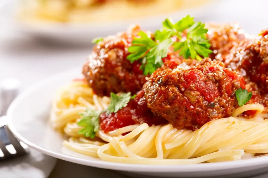 Plate of spaghetti topped with meatballs and marinara sauce, garnished with parsley.
