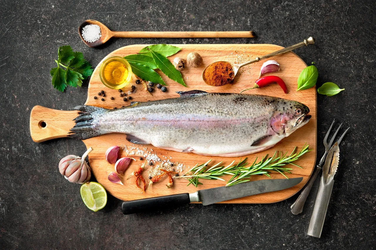 Fresh whole fish with herbs and spices on wooden boards.