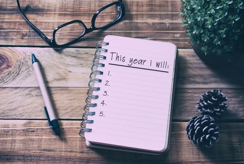 A notebook titled 'This year I will...' with a pen and glasses nearby.