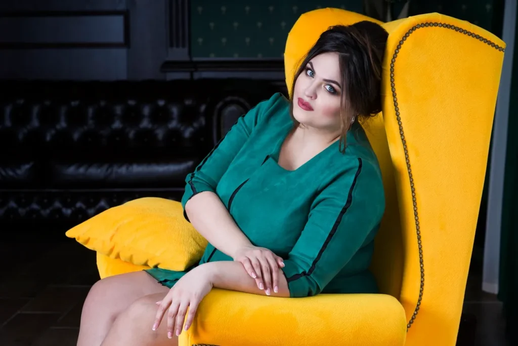Woman in green dress sitting comfortably on a yellow armchair.