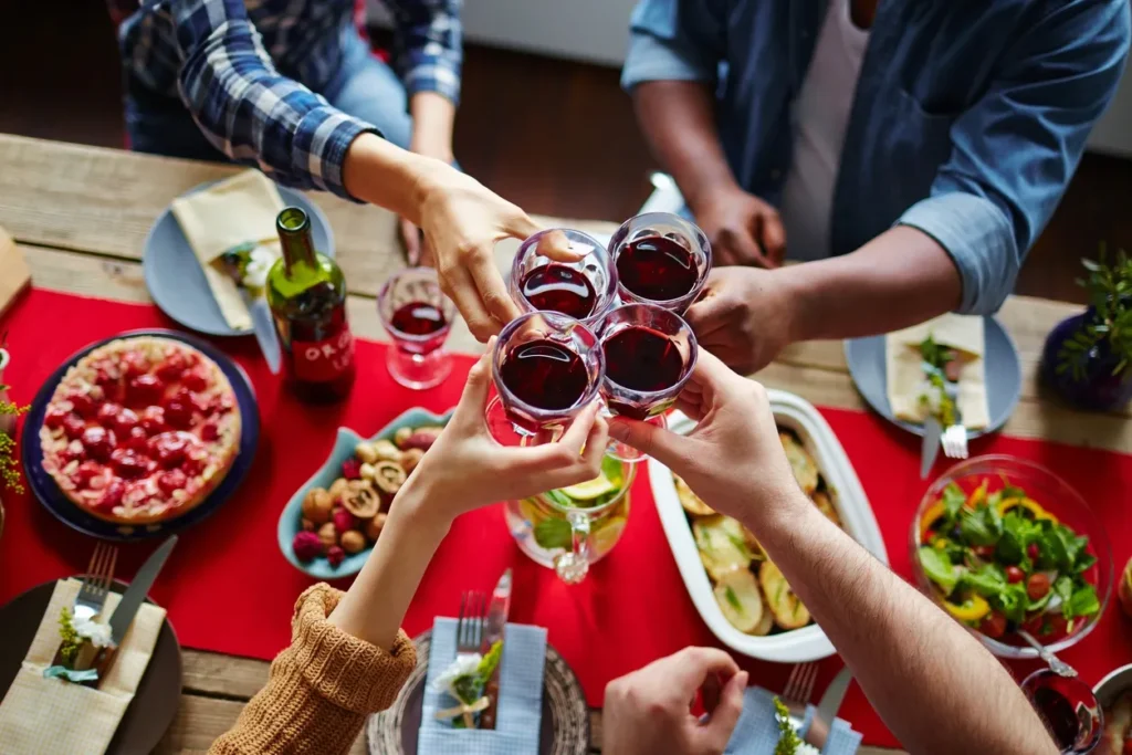 Friends clinking glasses filled with red wine in a lively gathering.