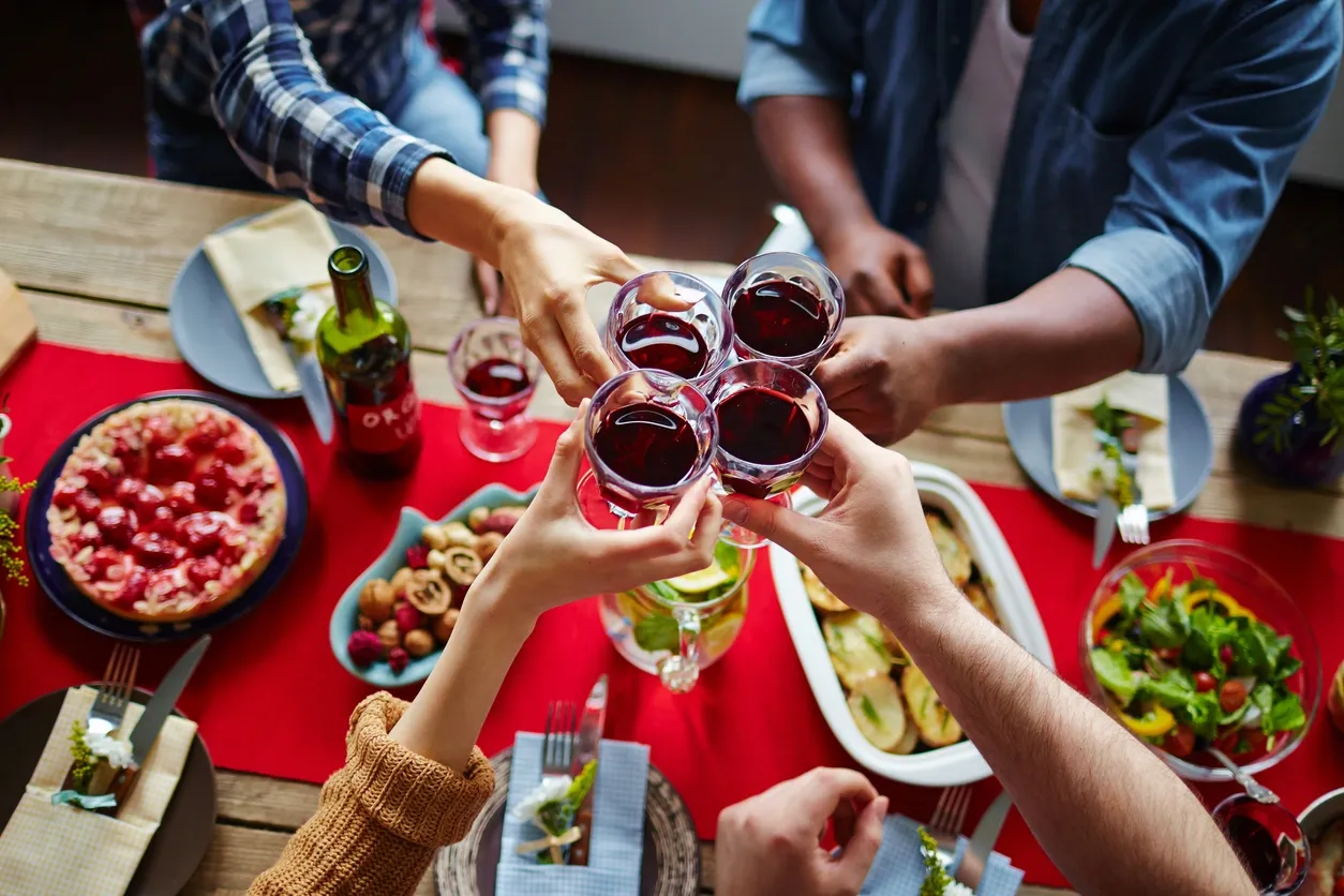 Friends clinking glasses filled with red wine in a lively gathering.
