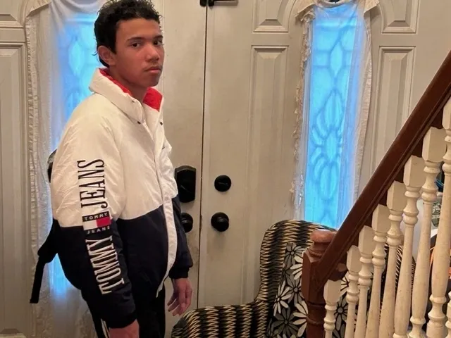 Young man posing indoors by the staircase and front door.