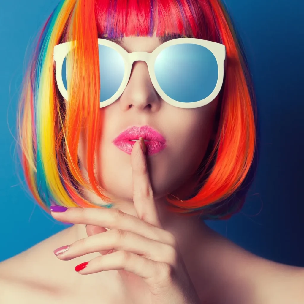 Woman with vibrant rainbow-colored bob haircut and reflective sunglasses.
