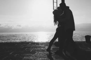 Silhouette of a couple sharing a romantic moment by the sea at sunset.