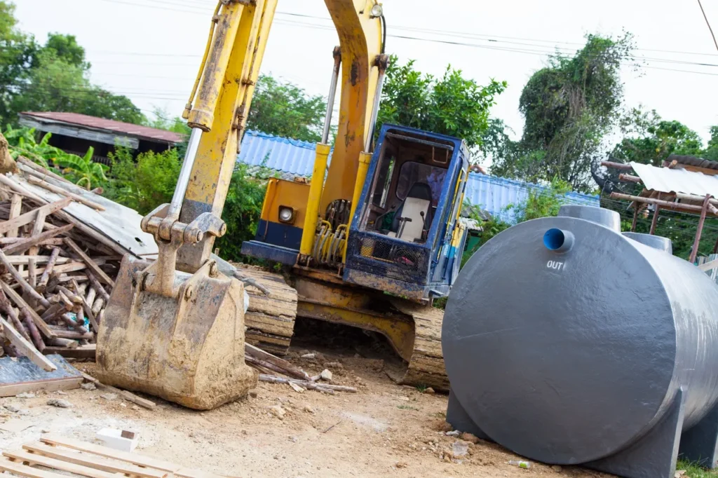 Yellow excavator and large cylindrical tank on a construction site.