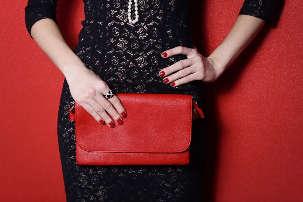 Woman in red dress holding a coffee cup and handbag.