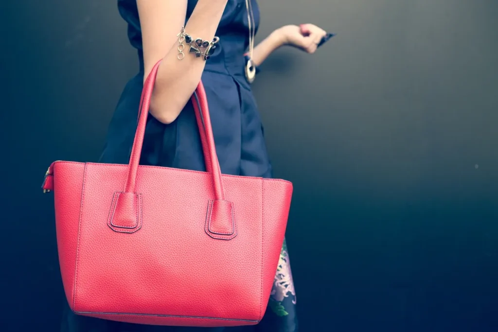 Woman in red dress holding a coffee cup and handbag.