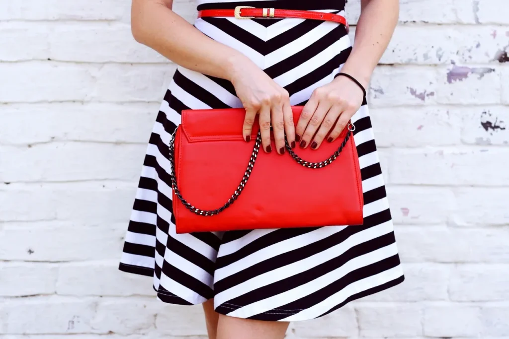 Woman in red dress holding a coffee cup and handbag.