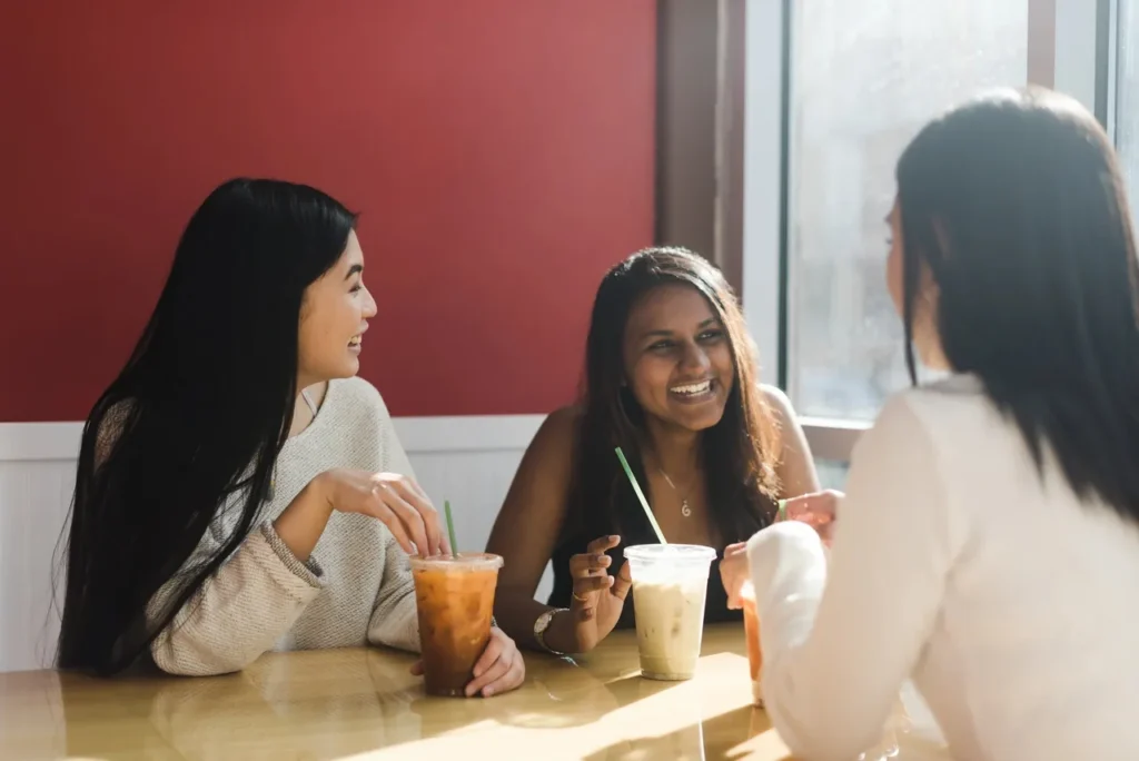 Three women enjoying drinks and conversation at a café.