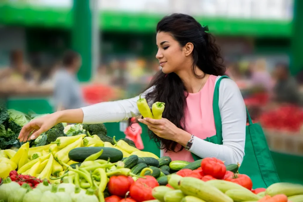 Woman selecting fresh vegetables at an outdoor market.