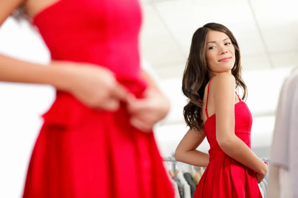 Woman in red dress holding a coffee cup and handbag.
