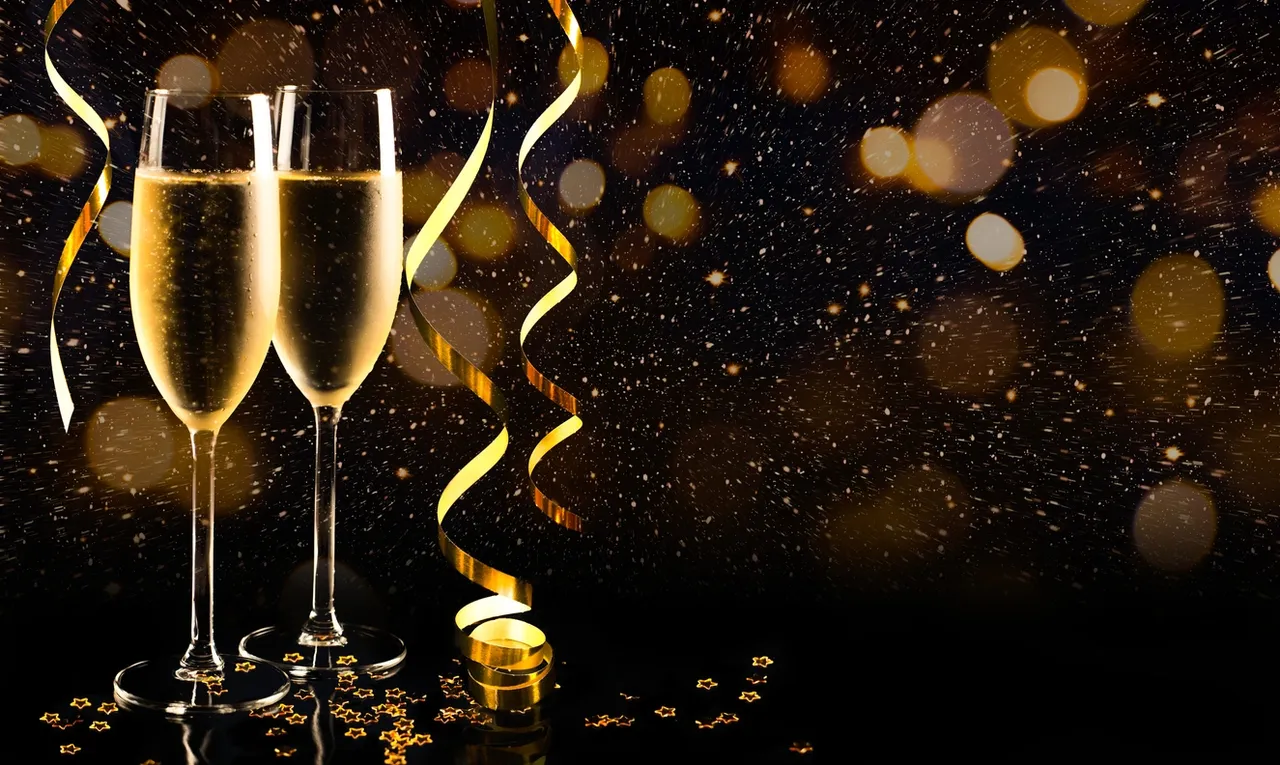 A glass of champagne with festive golden decorations and confetti.