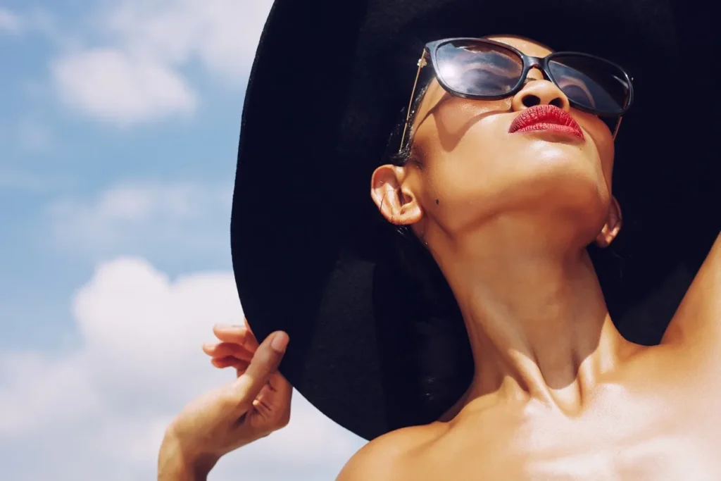 Woman wearing sunglasses and a black hat under a blue sky.