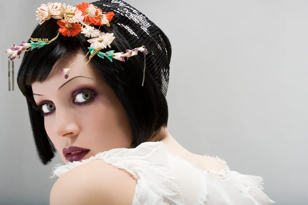 Portrait of a woman with floral headpiece and dramatic makeup.