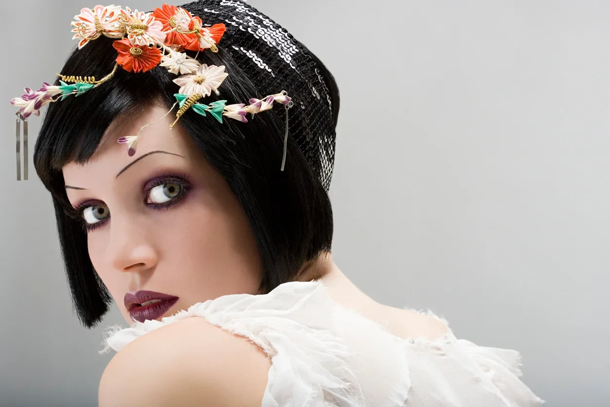 Portrait of a woman with floral headpiece and dramatic makeup.