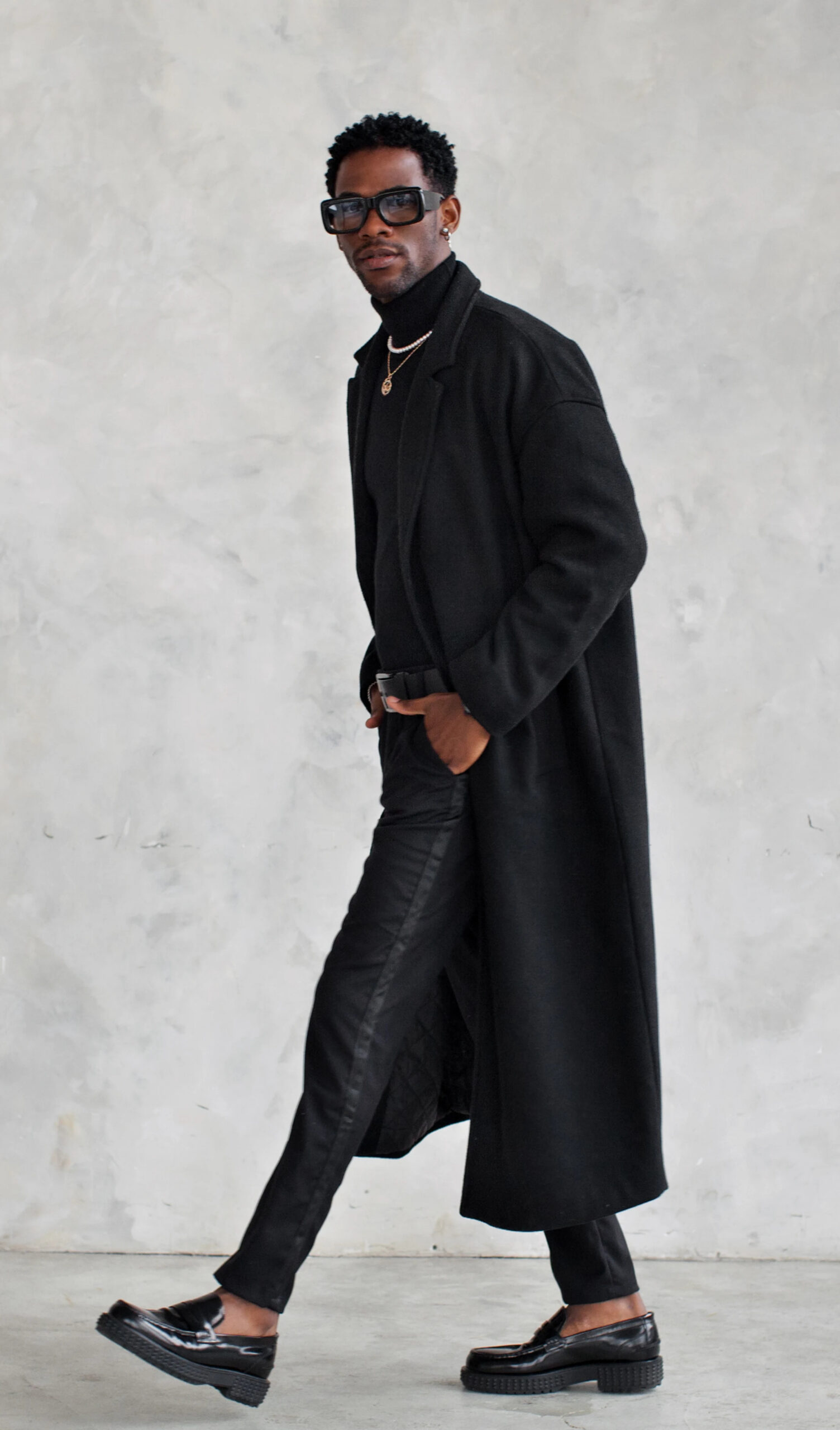 Person wearing long black coat and sunglasses